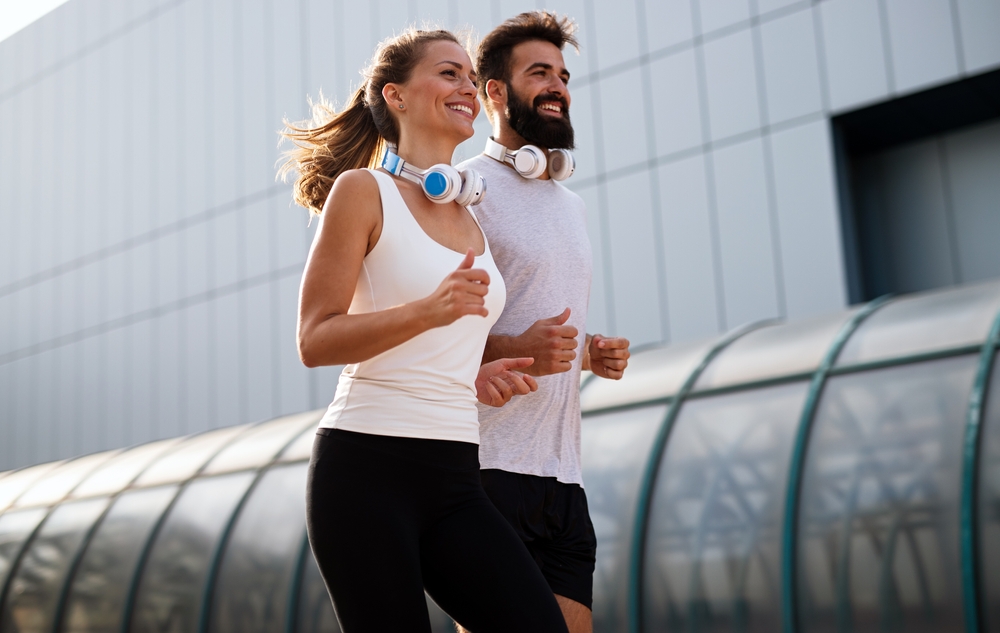 Smiling couple jogging together outdoors, showcasing an active lifestyle supported by proper chiropractic alignment – Chiropractor in Manahawkin, NJ.