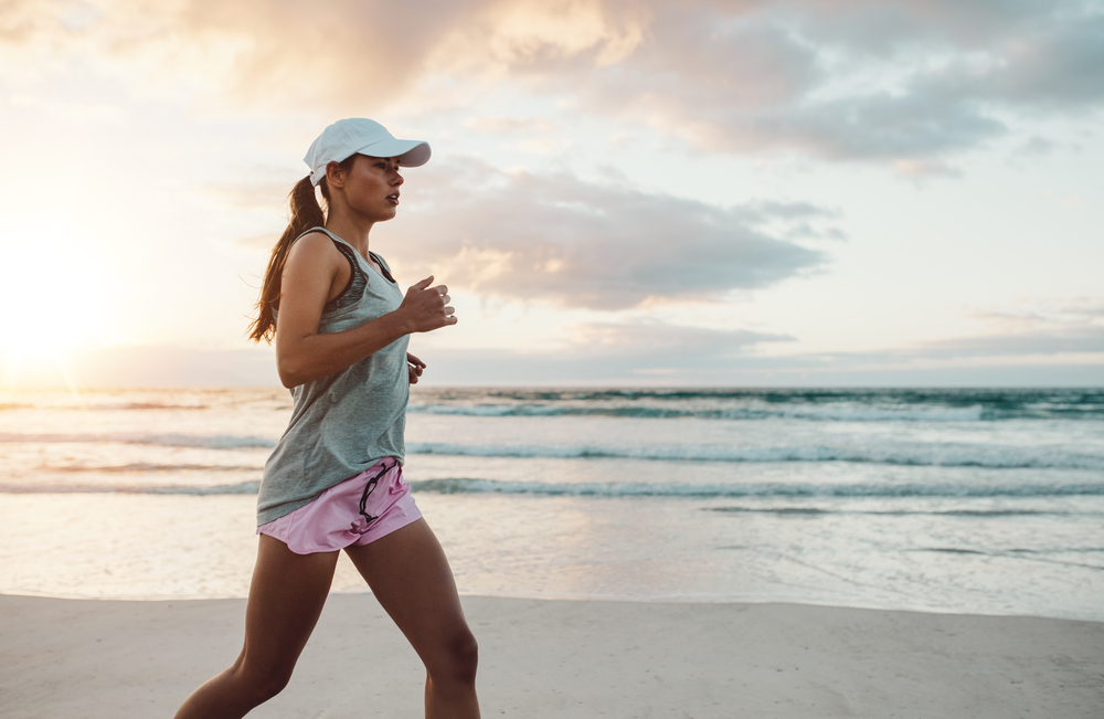 Woman jogging along the shoreline at sunrise, representing healthy movement, strength, and rehabilitation progress – Physical Therapy in Manahawkin, NJ.