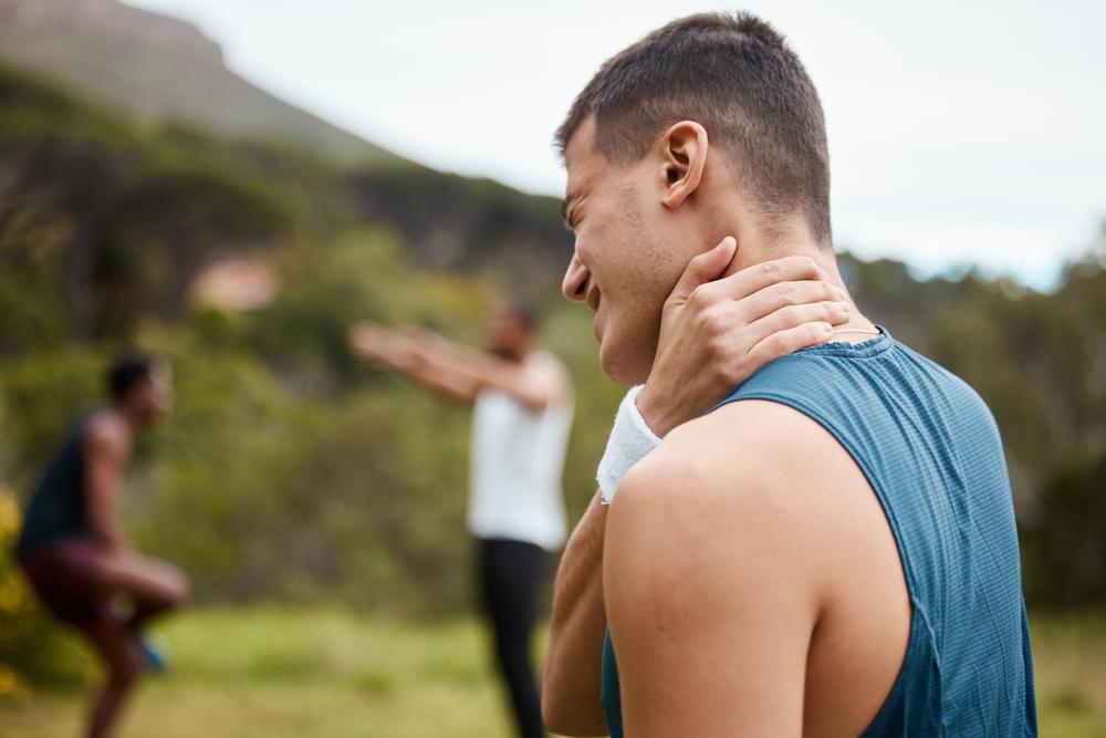Man holding his neck outdoors after exercise, symbolizing the need for chiropractic care and muscle tension relief – Chiropractor in Manahawkin, NJ.