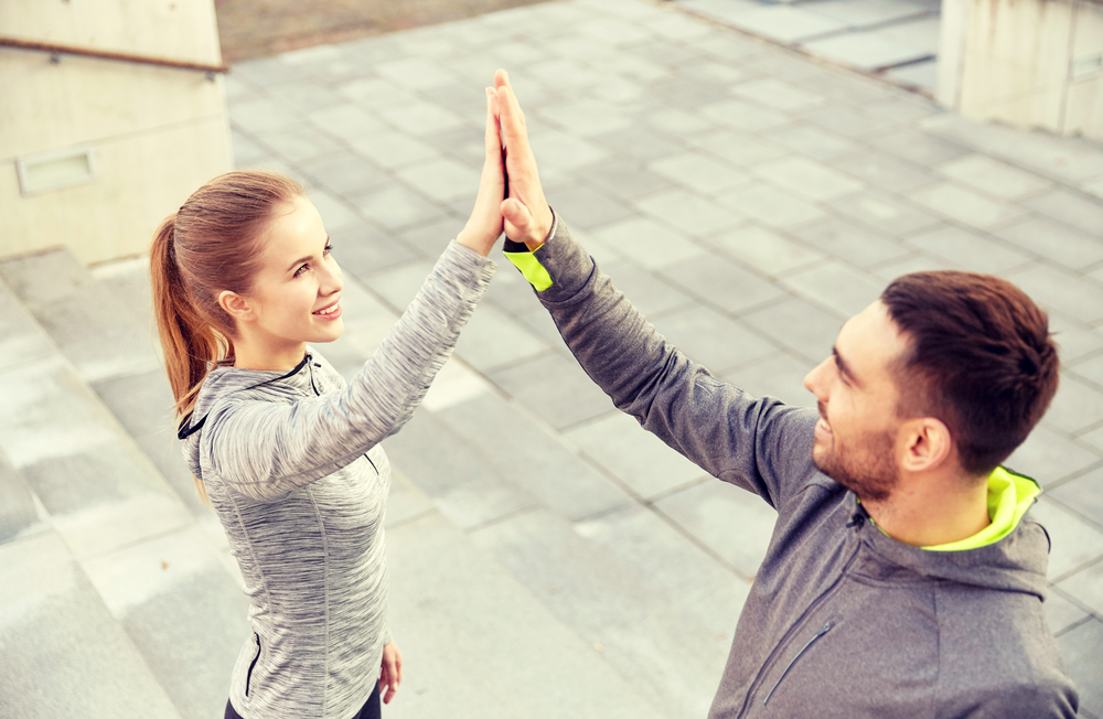 Two people high-fiving after a fitness session, representing teamwork, recovery, and spinal health improvement – Chiropractor in Manahawkin, NJ.